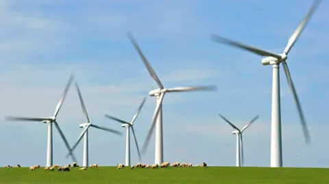 A windfarm is seen on Anglesey, north Wales with hills in the foreground