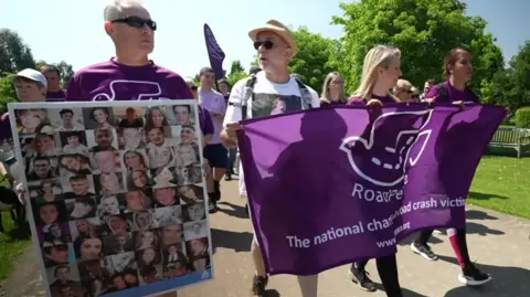 BBC Family members walking carrying banners and montage images of young car crash victims
