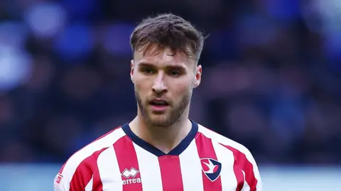 Sam Sherring wearing the red-and-white striped home kit of Cheltenham Town 