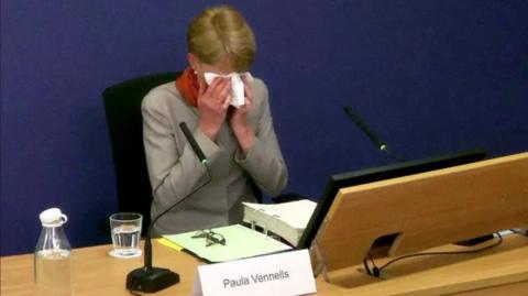 Paula Vennels crying with a tissue over her face