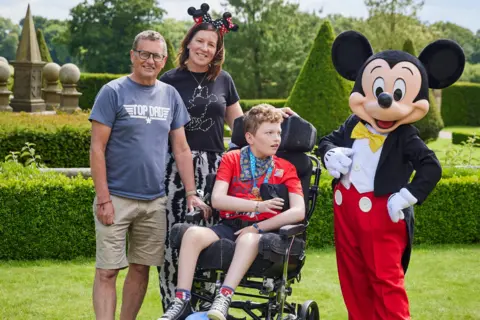 PA Media Barney with dad Andy, mum Beverley and Mickey Mouse