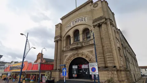 Google Maps A large building with neoclassical pillars and features is next to a colourful gaming arcade on Great Yarmouth's seafront.