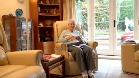 Woman sat in armchair reading her post