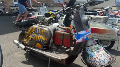 a colourful Lambretta has Bring Me Sunshine painted on the side