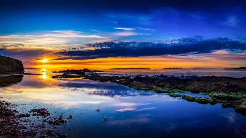 A golden sunset over dark blue water.