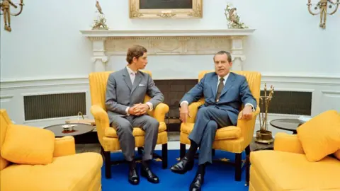 Getty Images In 1970, Charles was 21 years old when he sat in the White House Oval Office with President Richard Nixon. The two sit in yellow cushioned chairs, with blue carpet below.