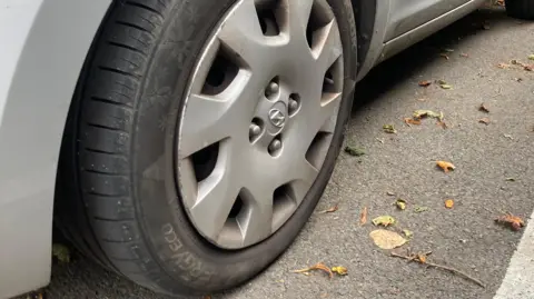 A generic picture of a car wheel on a road.