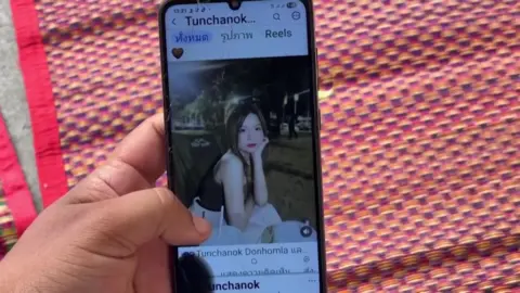Reuters A close-up shot of a mobile phone on which an Instagram account belonging to the victim shows an image of her. She is a young woman with long brown hair and is posing with her chin rested on her hand in the evening.