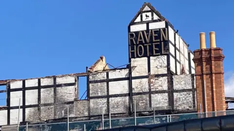 A shot of the front of the old Raven Hotel - the words 'Raven Hotel' can be seen on the old black and white period frontage.