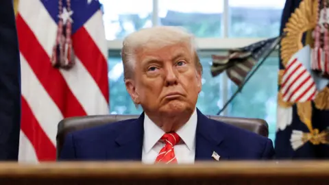Donald Trump sits in the Oval Office