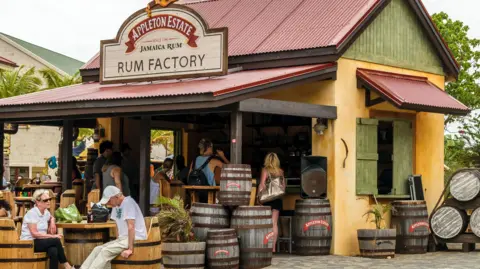 Getty Images/Debbie Ann Powell A Shack Menjual Appleton Estate Rum dengan Turis Duduk di luar. 