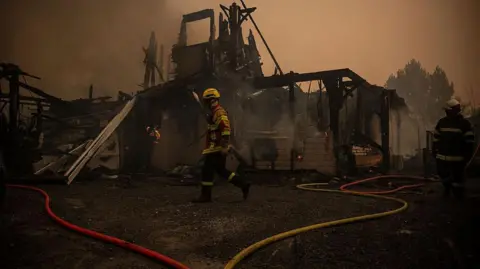 A firefighter walks in front of a burnt out building