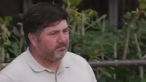Gary O'Grady has a light polo shirt, brown hair and brown goatee beard with flecks of whites.