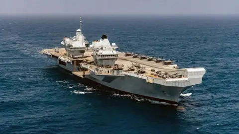 An aerial image of the HMS Prince of Wales aircraft carrier taken from above. The ship is on an open ocean.