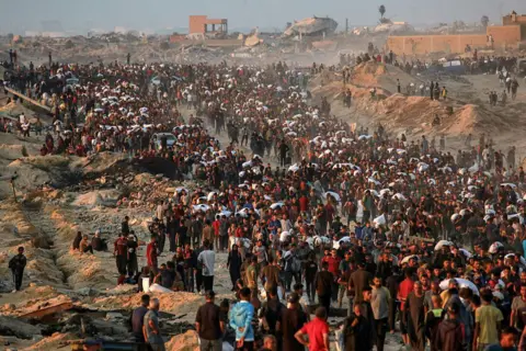 AFP People carrying sacks of flour walk along Rashid Street, in northern Gaza, after aid lorries brought in flour via the Erez West crossing (17 June 2025)