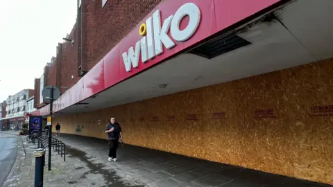 La enorme tienda Wilko en Gloucester. El logotipo todavía está pintado en la gran fachada roja, pero las ventanas están tapiadas.