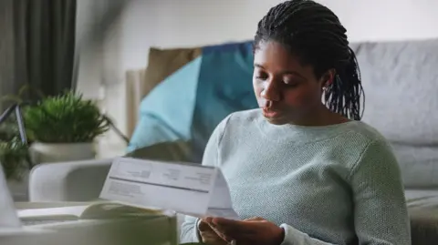 Getty is looking at a bill to a person because he sits in front of a couch