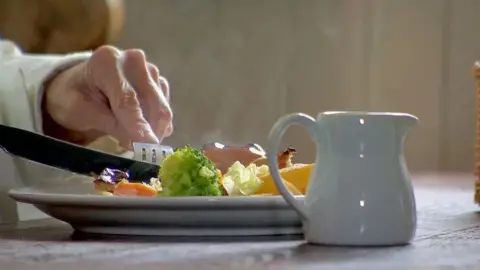 BBC A closeup of someone digging into a plate of food