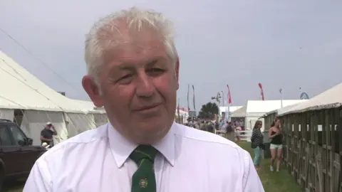 Farmer Martin Howlett wearing a white shirt with a green tie looking away from the camera. 