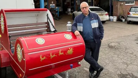 Belper and Duffield Rotary Club The red sleigh, with rotary club member Dave stood next to it, having its annual check-up outside a garage called Amber Tyres in Ripley. 