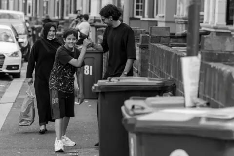 Khuram Mirzal A young child actor fist-bumps the director on a residential street during filming of Ish.
