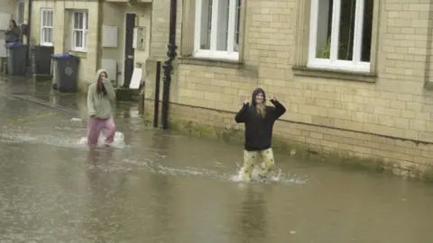 LDRS Two girls wading in water after flooding in Calne with the water up to above their ankles