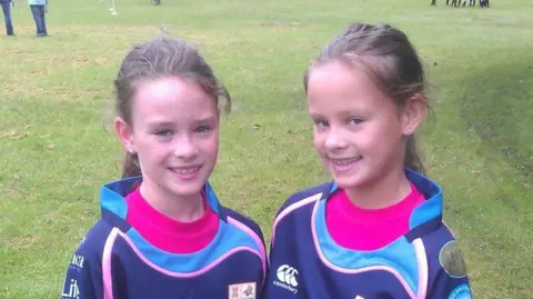 Ffion Jones An old image showing Ffion and Celyn standing on a field smiling at camera in rugby kit. 