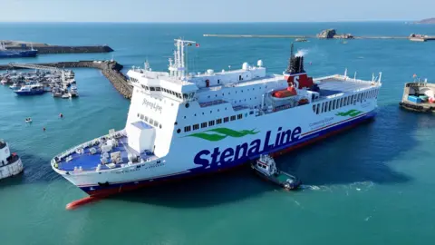The photo shows the boat the Stena Vinga. It is a large ferry and is stopped in a harbour. The water is light blue.