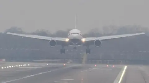 PA Media A front-on angle of a British Airways just above the runway at Gatwick Airport as it lands during foggy conditions