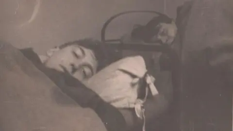 IBCC A sepia picture of two soldiers lying in bunk beds looking into the camera