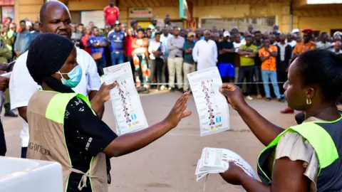 Reuters Election officials holding ballot papers outside a polling station in front of crowds of people