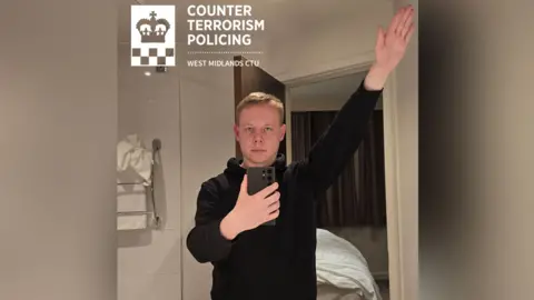 West Midlands CTU A picture showing Parslow giving a Nazi salute in front of a mirror in a bathroom. He has short blond hair and is wearing a black hoodie.