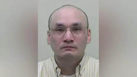 Northumbria Police mugshot of Kwan. he is bald and wears glasses