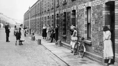 Getty Images A black and white old image of some old residents of Llewellyn Street in Port Talbot outside their terraced houses