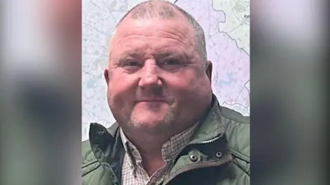 Paul Clark Paul Clark with short grey hair wearing a green coat