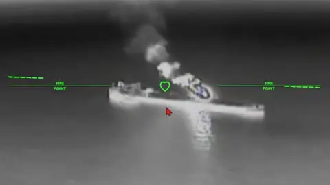 A still image of an oil tanker under attack from a drone in a black and while nighttime image
