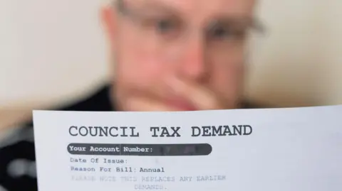 Council tax demand in the foreground with blurred picture of worried man looking at it.