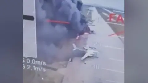 Planes on fire on runway with smoke pluming around them