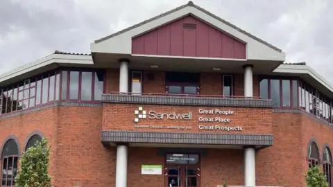 A building showing the Sandwell council logo and words including Sandwell. There are windows going across most of the visible section of the highest floor.