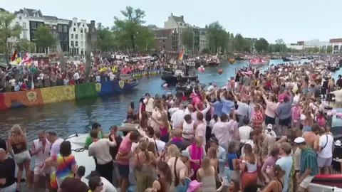 Revellers line Amsterdam canal to watch the annual Pride boat parade