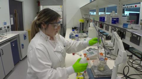 Researcher holding equipment over a beaker inside the cancer research facility
