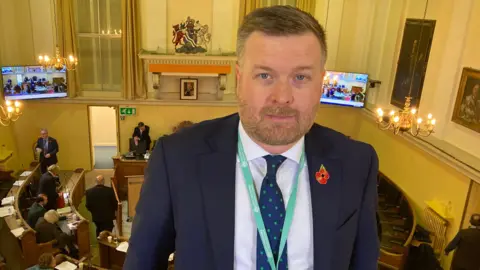 Councillor Liam Walker stands on a raised balcony at Oxfordshire County Council.