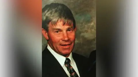 Family Handout Man wearing a suit and tie smiling at the camera