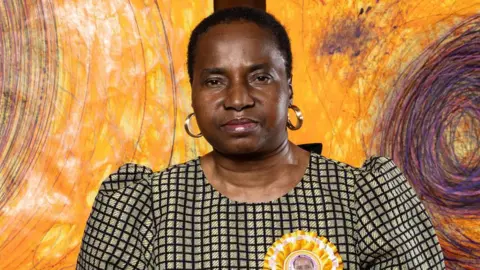 PA Media Nnena Kalu standing in front of her giant orange swirl pattern drawings after the Turner Prize announcement