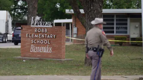 A police officer standing near Robb Elementary School in Uvalde, Texas.