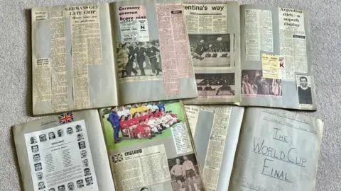 A photo of four scrapbooks opened up with newspaper cuttings and other photos and tickets.
