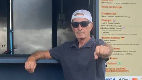 Charlie Pearson Charlie Pearson, wearing a baseball cap in front of his sausage stand.