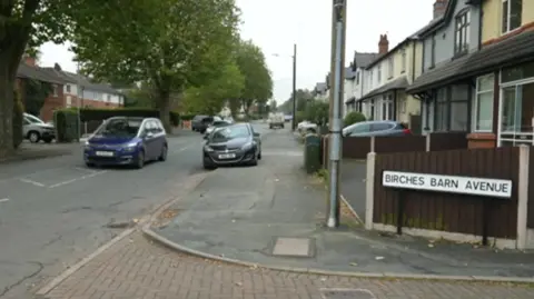 BBC A residential street with houses on either side and a number of large trees 