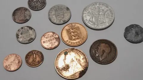 A mixture of coins ranging in colour - including copper and silver - and showing a range of use with some shiny and other worn and pitted