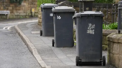 Three black bins on pavements outside homes